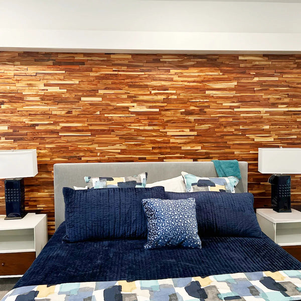 Bedroom with wooden wall paneling, bed with blue bedding and pillows, and nightstands with lamps.