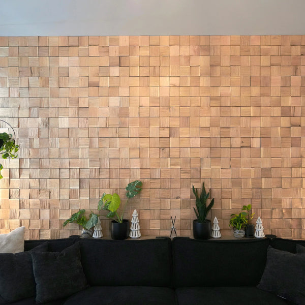 Wooden wall paneling in a living room with a black sofa and decorative plants.