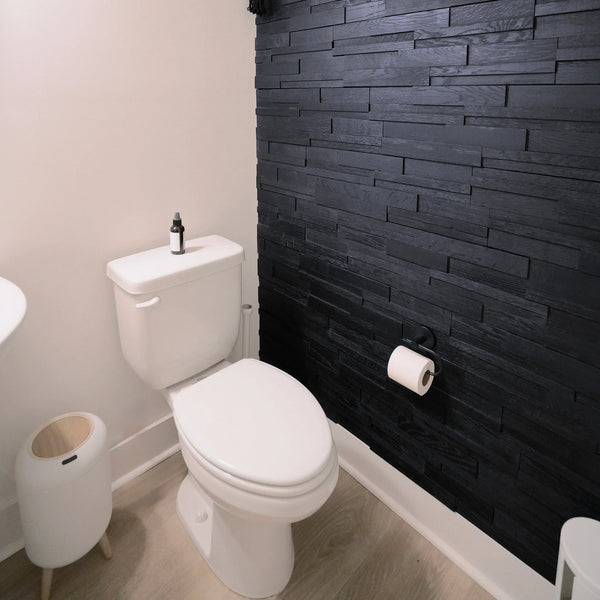Bathroom with a toilet against a black brick wall.