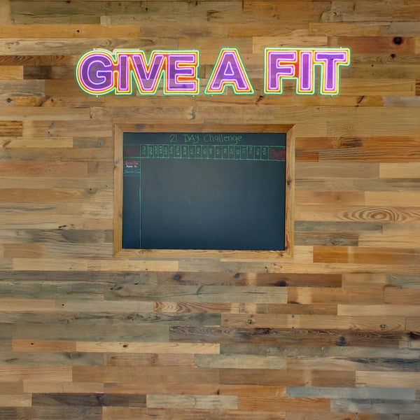 Wooden wall with a blackboard and 'Give a Fit' neon sign.