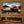 TV mounted on a wooden wall displaying a car, below which is an electric fireplace.