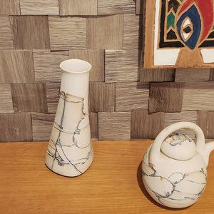 Two ceramic vases on a wooden surface with a textured wall in the background