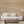 White sofa with beige pillows in a living room setting with wooden coffee table and lamp.