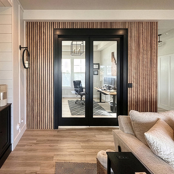 Living room with a view of an office through a glass door.