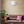 Living room with brown sofa, pink pillow, and white pendant light.