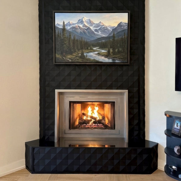 Modern fireplace with black quilted surround and mountain landscape painting above.
