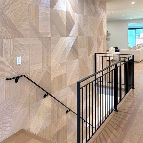 Staircase with geometric wall tiles and black railing in a modern interior setting.