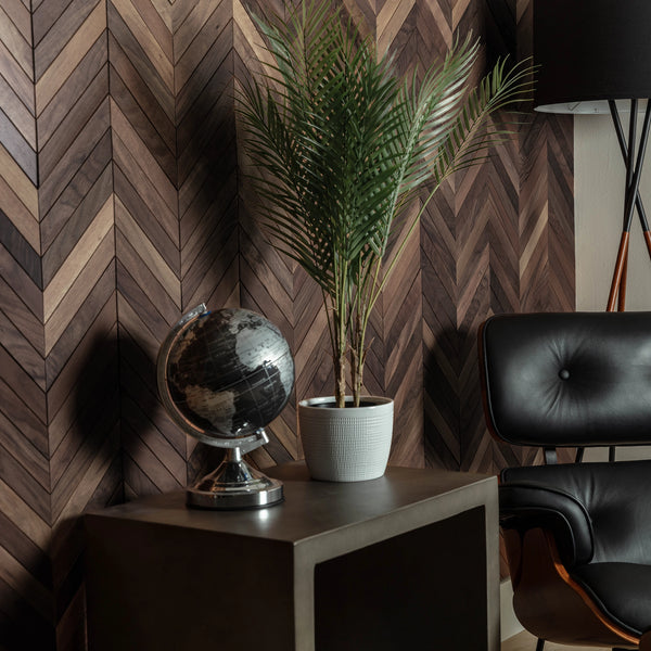 Room interior with a chevron-patterned wall, black chair, potted plant, and globe.