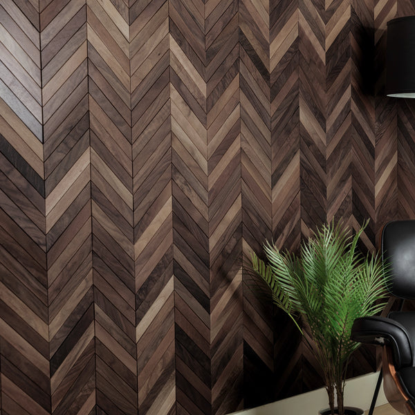 Wooden wall panel with chevron pattern in a room with a plant and chair.