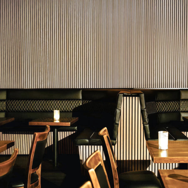 Restaurant interior with black leather booths, wooden chairs, and striped walls.