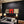 Modern living room with a black textured wall, gray sofa, and abstract art.