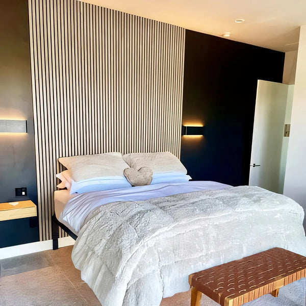 Modern bedroom with a bed, striped wall, and wooden bench.