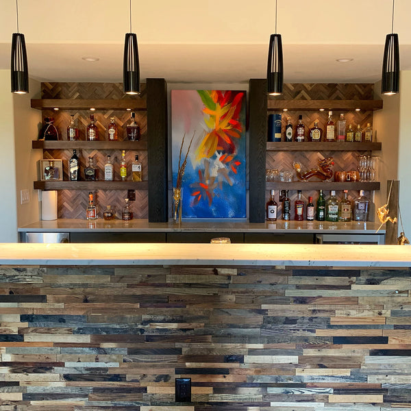 Bar area with wooden shelves, bottles, and a colorful painting on a wall.