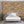 Bedroom with a wooden wall paneling and a bed with gray headboard and white bedding.