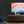 Colorful abstract painting on a black wall above a wooden console table with decorative vases.