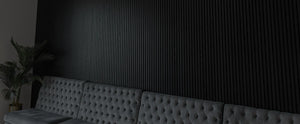 Gray tufted sofa against a dark textured wall